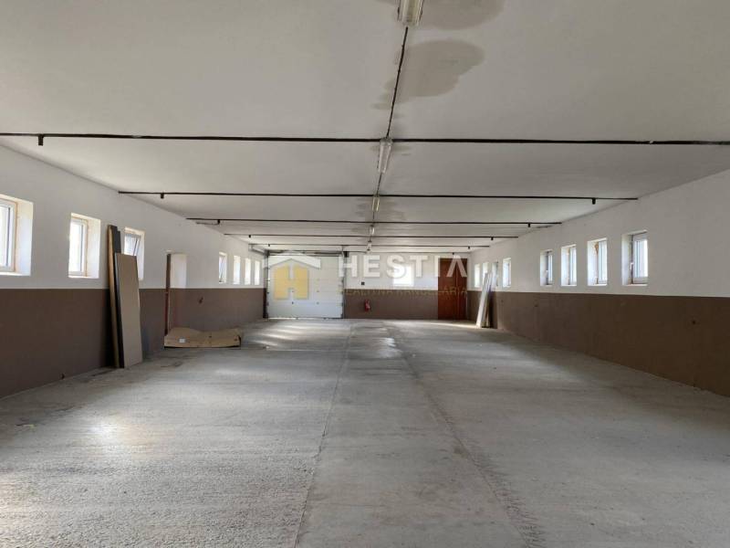 Tágas tér raktárakban és csarnokokban, sor ablakokkal és betonpadlóval.