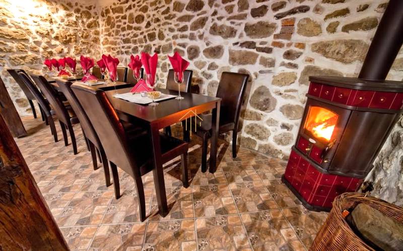 Rusztikus gasztronómiai terek kandallóval, kőfallal és asztalokkal, szalvétákkal.