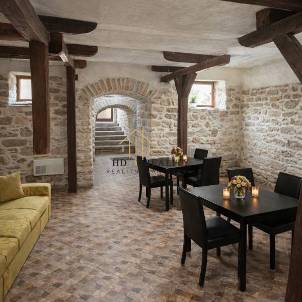 Vendéglátóhely belső terek kőfalakkal és fa dekorációjú padlóval, asztalok virágokkal.