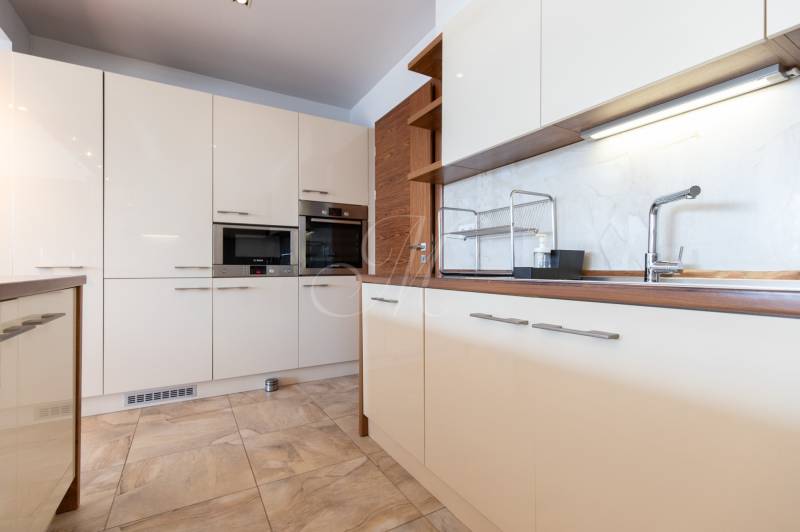 Konyha egy kétszobás lakásban fehér szekrényekkel és készülékekkel.