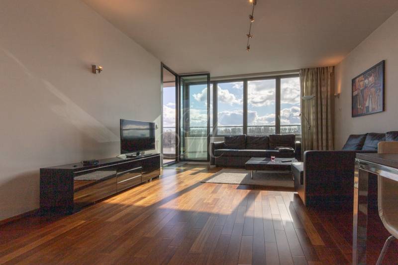 Nappali egy kétszobás lakásban, fa mintázatú padlóval és nagy ablakokkal.