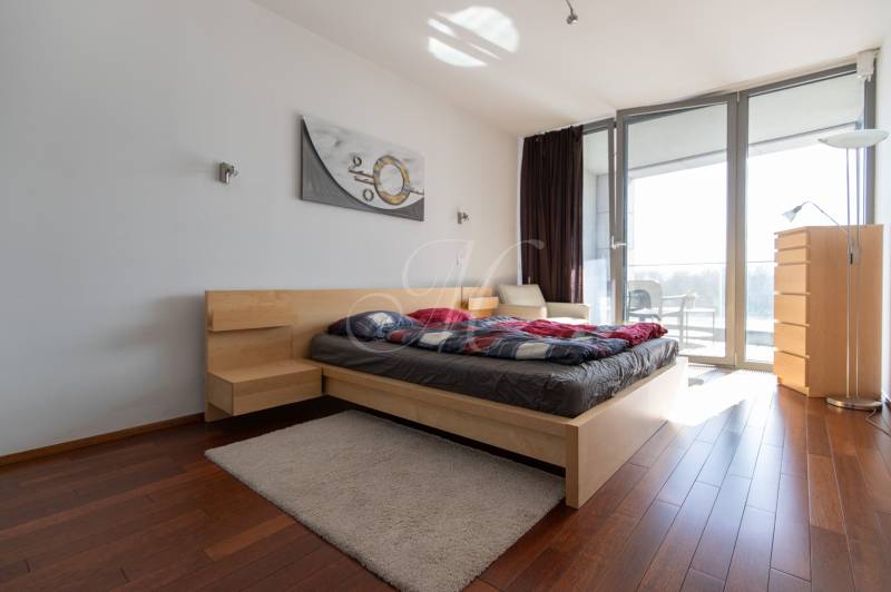 Hálószoba egy kétszobás lakásban fa dekor padlóval és tágas ablakokkal.