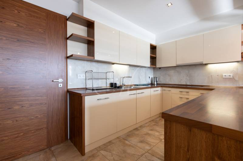 Konyha egy kétszobás lakásban világos szekrényekkel és fa dekorációjú padlóval.