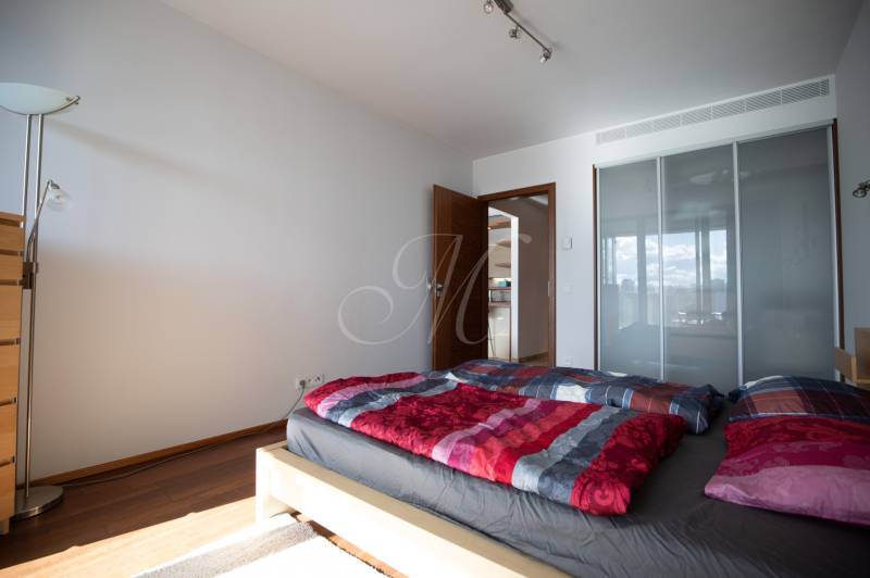 Hálószoba egy kétszobás lakásban, fa dekor padlóval, ággyal és szekrénnyel.