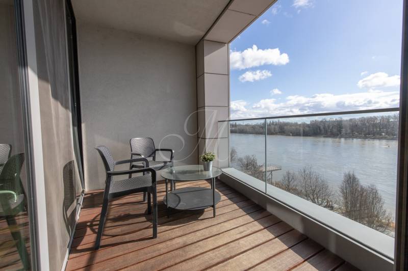 Erkély egy 2 szobás lakásban, kilátással a folyóra, fa dekorációjú padlóval.