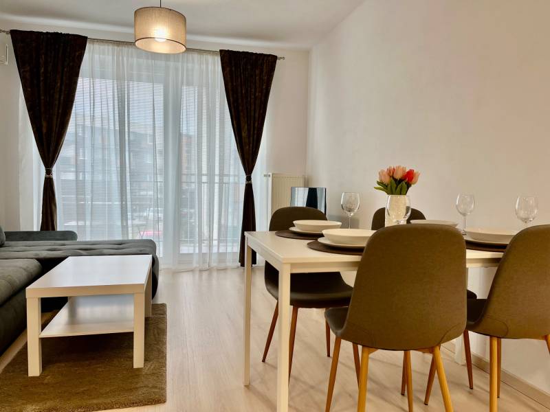 2 szobás lakás fa mintázatú padlóval, étkezőasztallal és kanapéval.