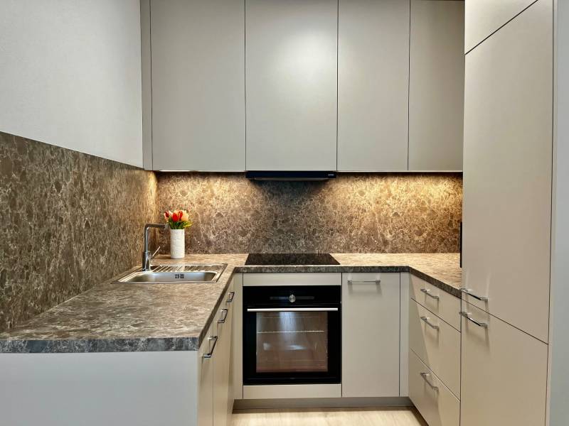 Konyha egy 2 szobás lakásban virágokkal, márványburkolattal és háztartási gépekkel.