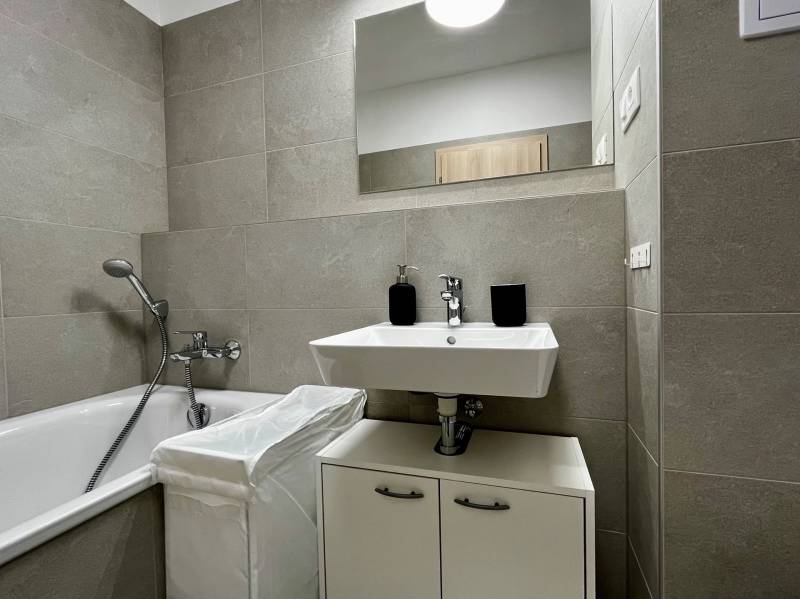 Fürdőszoba káddal és mosdóval egy kétszobás lakásban kerámia csempékkel.