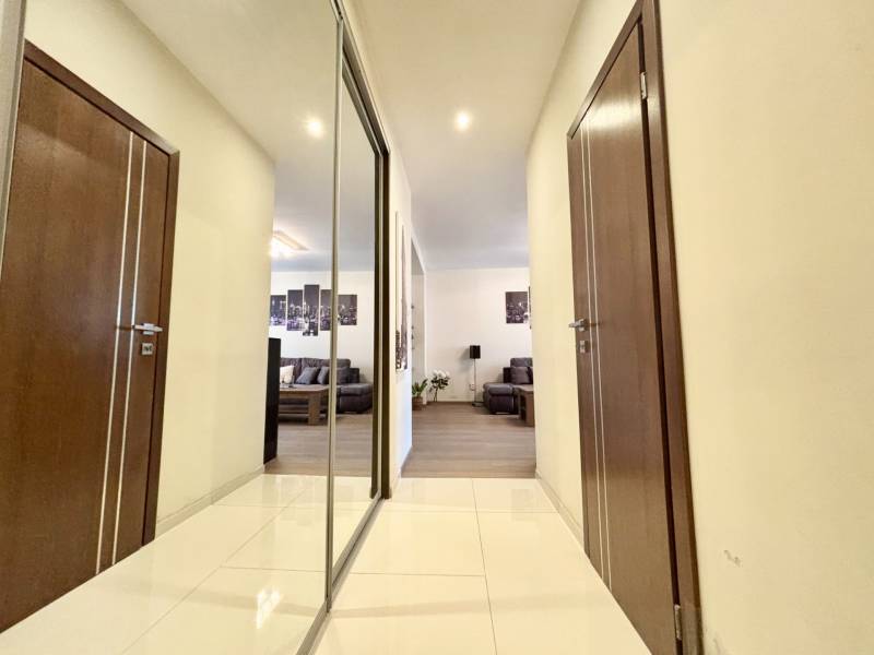 Folyosó egy 2 szobás lakásban csempével, tükörrel és kilátással a nappalira.