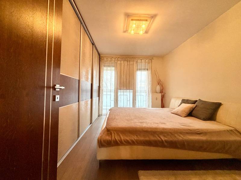 Hálószoba egy kétszobás lakásban nagy ággyal és fa dekorációjú padlóval.