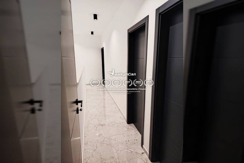 Folyosó egy családi házban csempével és sötét ajtókkal.