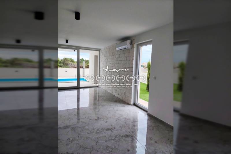 Családi ház belső tere légkondicionálással, nagy ablakokkal és kilátással a medencére.