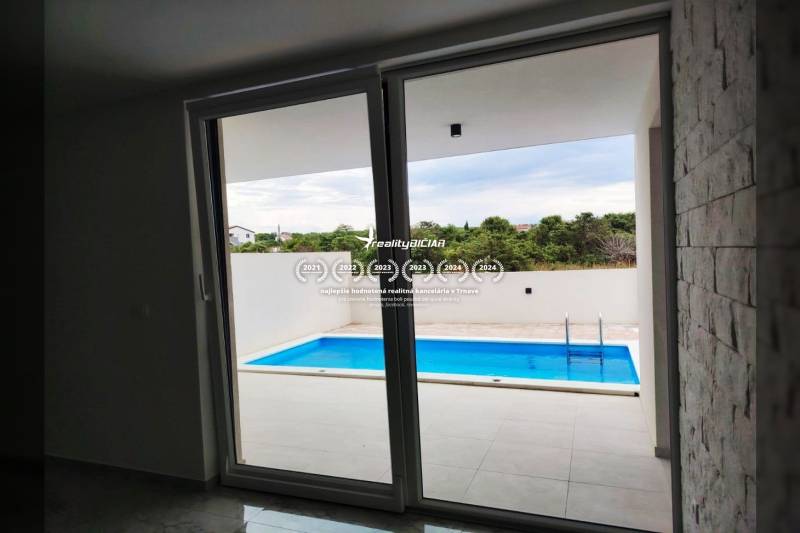 Kilátás a családi házból a teraszra medencével, fa dekorációjú padlóval.