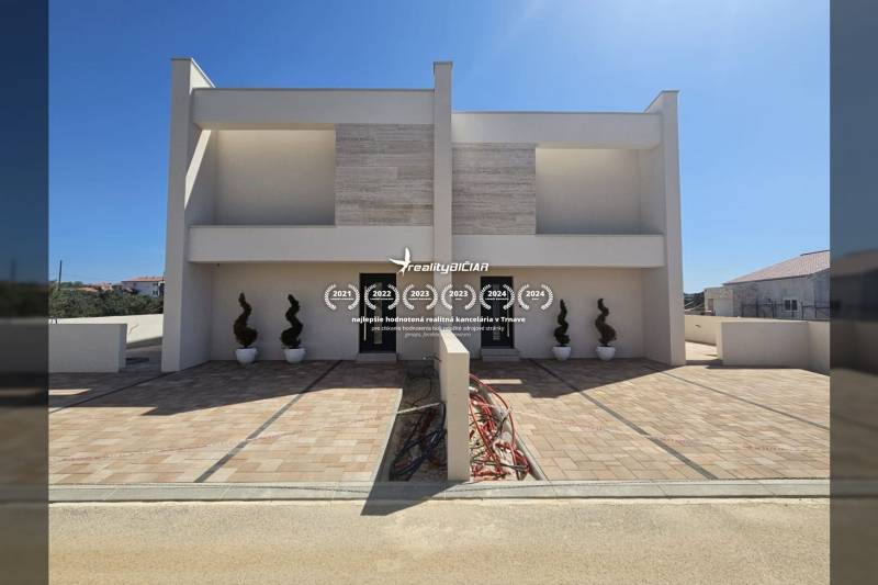 Családi ház a Mulo utcában, Vrsi-ben, burkolt sétánnyal és dekoratív növényekkel.