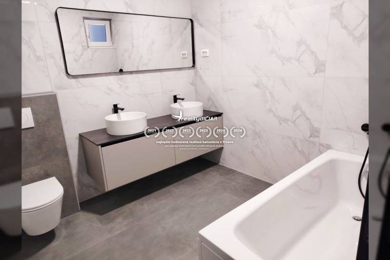 Családi ház fürdőszobája ovális mosdókkal, tükörrel és káddal.