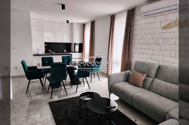 Nappali konyhával családi házban; márvány padló, fehér szekrények, zöld székek.