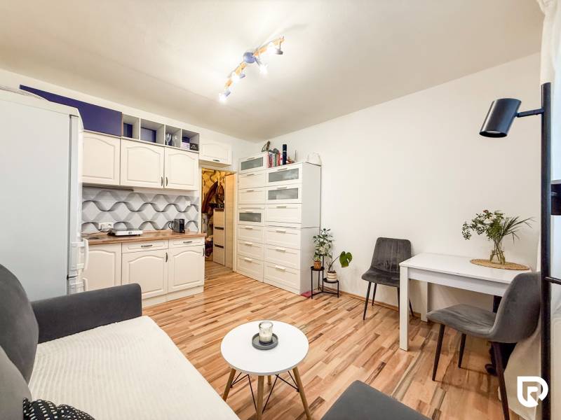 Garzonlakás konyhasarokkal, asztallal és fa dekorációjú padlóval.