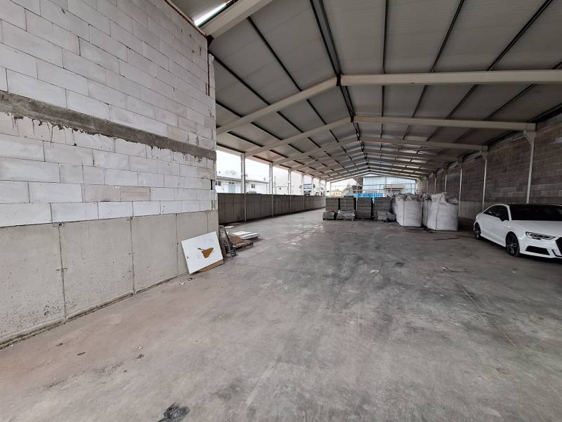 Raktárakban és csarnokokban látható autó, építőanyag és üres tér.