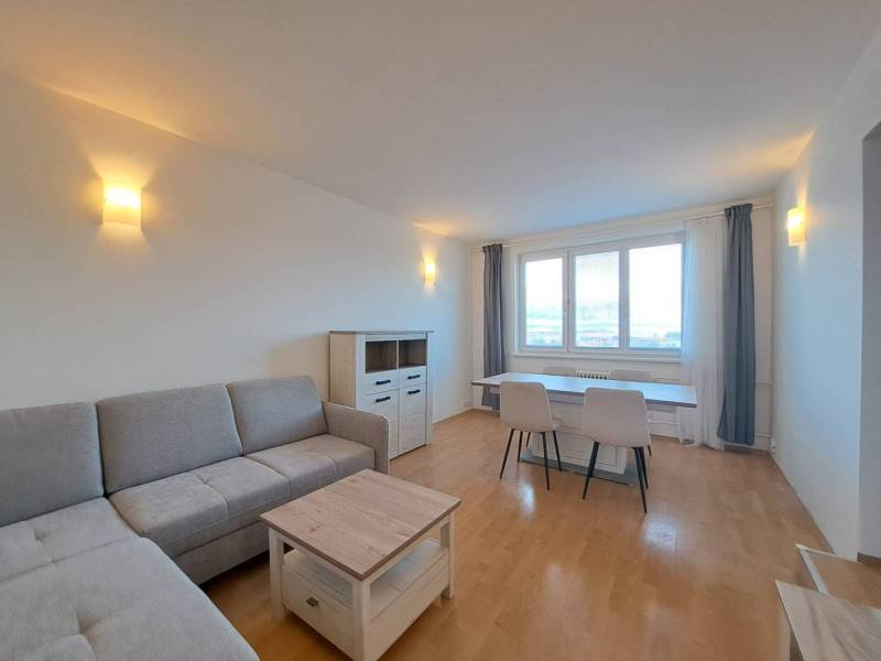 Nappali egy 4 szobás lakásban, fa dekoros padlóval és szürke kanapéval.