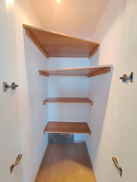 Beépített polcokkal ellátott gardrób egy négy szobás lakásban, fa dekor padlóval.