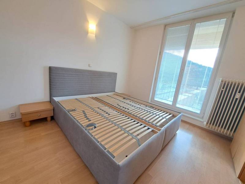 Hálószoba egy 4 szobás lakásban ággyal és éjjeliszekrénnyel, fa dekoros padlóval.