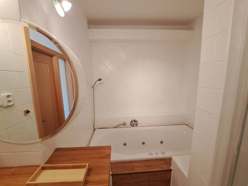 Fürdőszoba tükörrel és káddal egy 4 szobás lakásban; fa dekoráció használata.