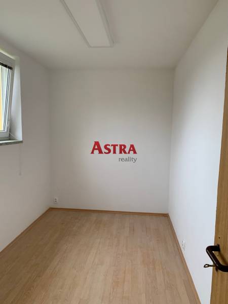 Kis szoba fehér falakkal és fa dekorációjú padlóval.