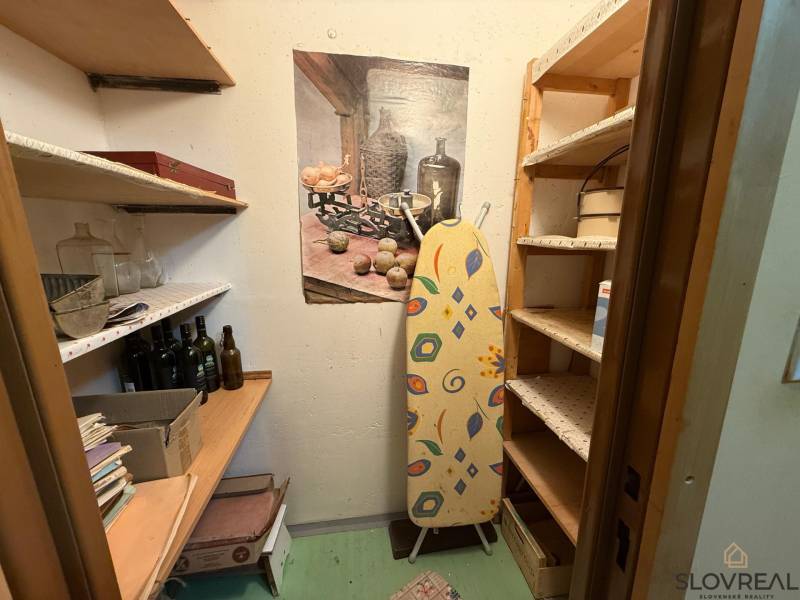 Tárolóhely polcokkal és vasalódeszkával egy háromszobás lakásban.