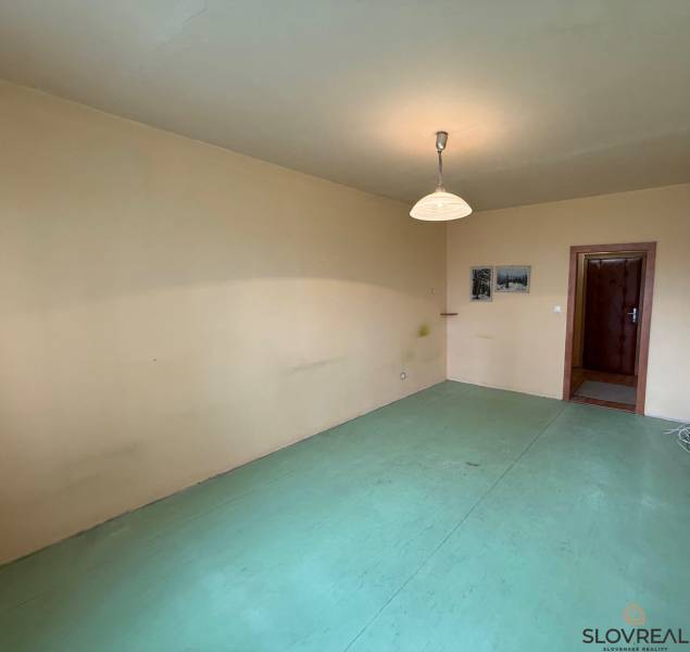 Szoba egy háromszobás lakásban semleges falakkal és világos padlóburkolattal.