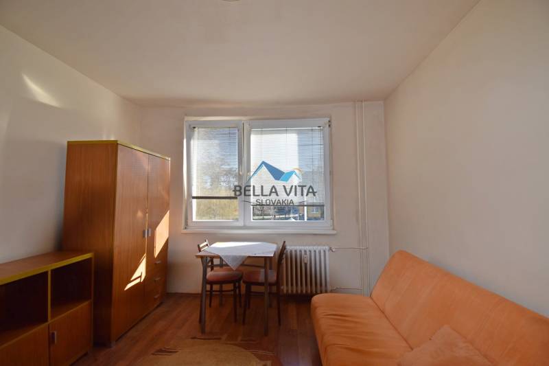 Studiolakas kanapéval, asztallal és szekrénnyel, fa dekoros padlóval.