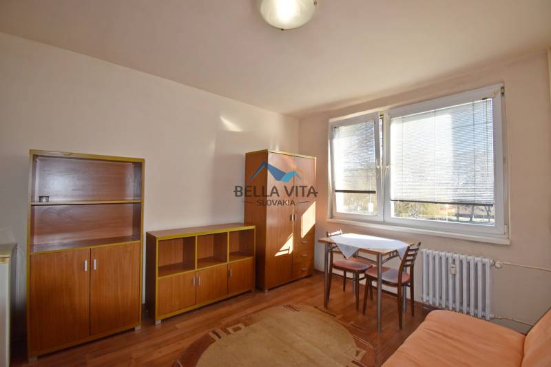 Garzonlakás bútorokkal, asztallal és székekkel, kiegészítve fa dekorációjú padlóval.