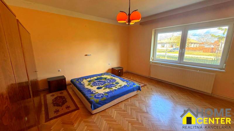 Hálószoba egy családi házban, fa dekor padlóval és narancssárga falakkal.