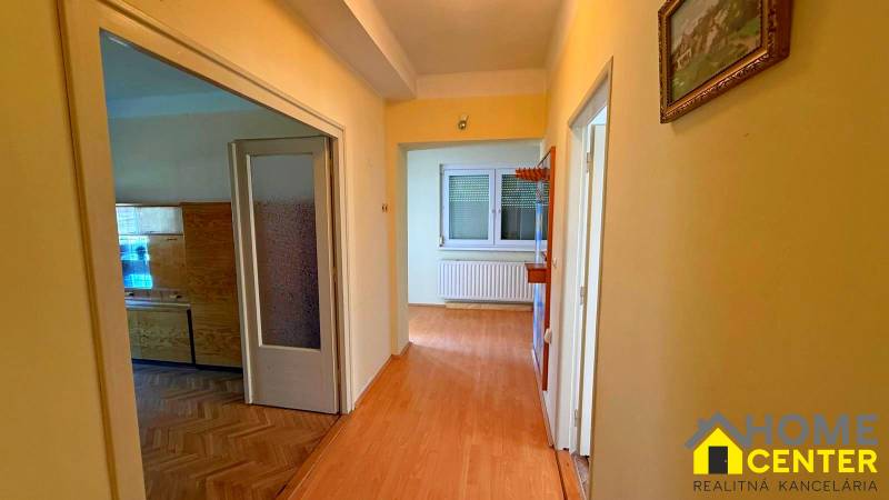 Egy családi ház folyosója fa dekorációjú padlóval és egy képpel a falon.