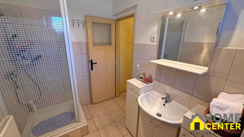 Fürdőszoba családi házban mosdóval, zuhanyzóval és csempével.