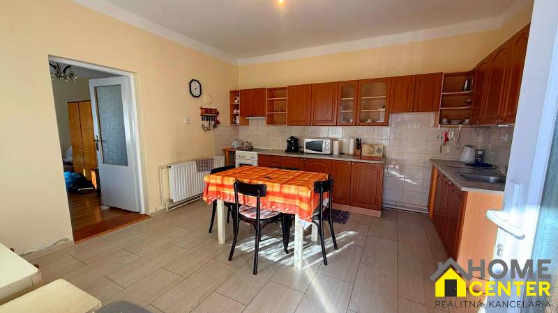 Konyha egy családi házban fa dekorációval és narancssárga terítővel az asztalon.