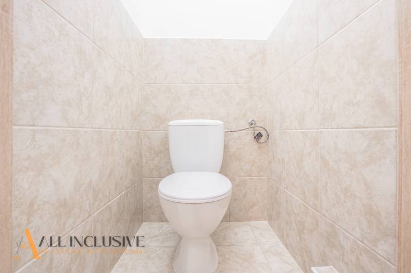 Világos csempékkel burkolt WC egy épületben.