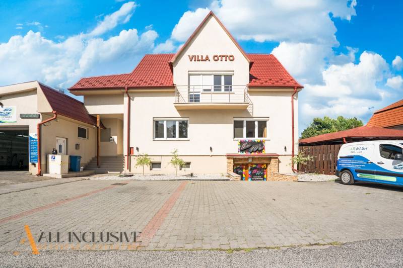 Piros tetős épület és kijelölt parkoló Dunaszerdahelyen.