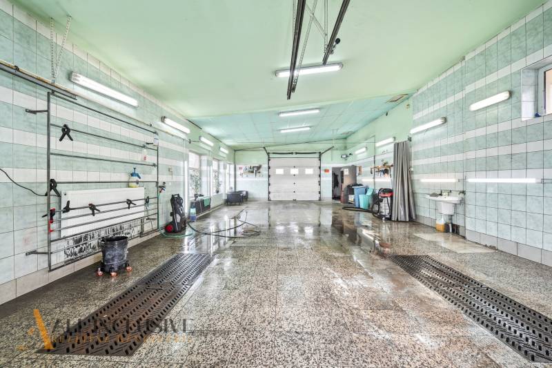 Belső mosócsarnok nedves padlóval és mennyezeti fénycsövekkel.