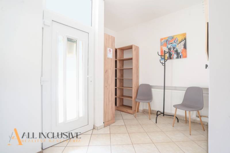 Az épület belseje bejárati ajtóval, csempével, polccal, két székkel és fogassal.