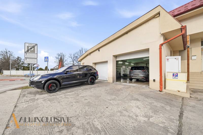 Épület Dunaszerdahelyen, autókkal a garázsok előtt és közlekedési táblákkal.