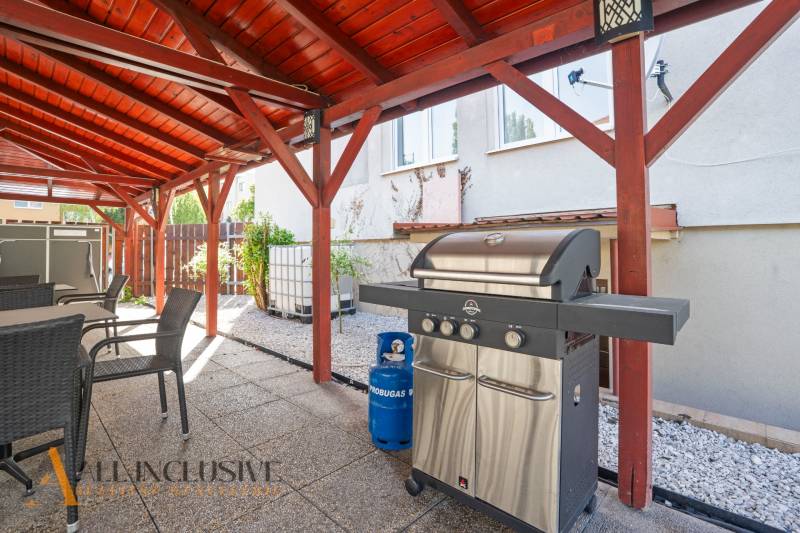 Pavilon Dunaszerdahelyen grillel és kerti bútorokkal, kavicsos ágy.