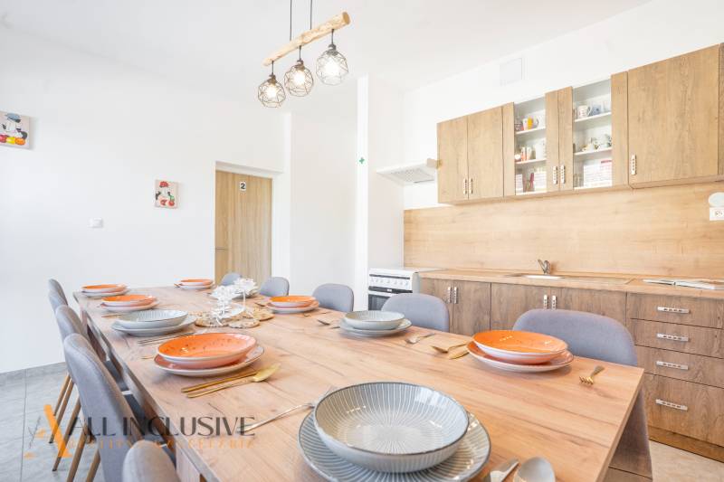 Konyha az épületben, fa szekrények, nagy asztal fa dekor padlóval.