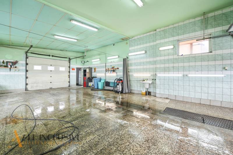 Egy helyiség az épületben nedves csempével, mosdóval és egy tömlővel a falon.