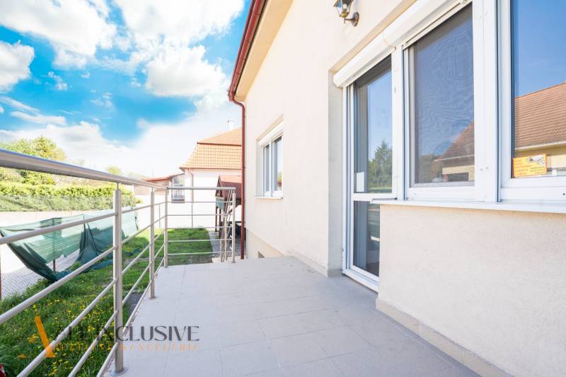 Épület Dunaszerdahelyen terasszal és korláttal, égbolt felhőkkel.