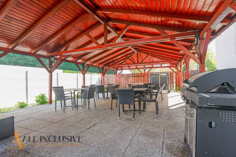 A Dunaszerdahelyi épület kültéri terasza fa tetővel és grillel.