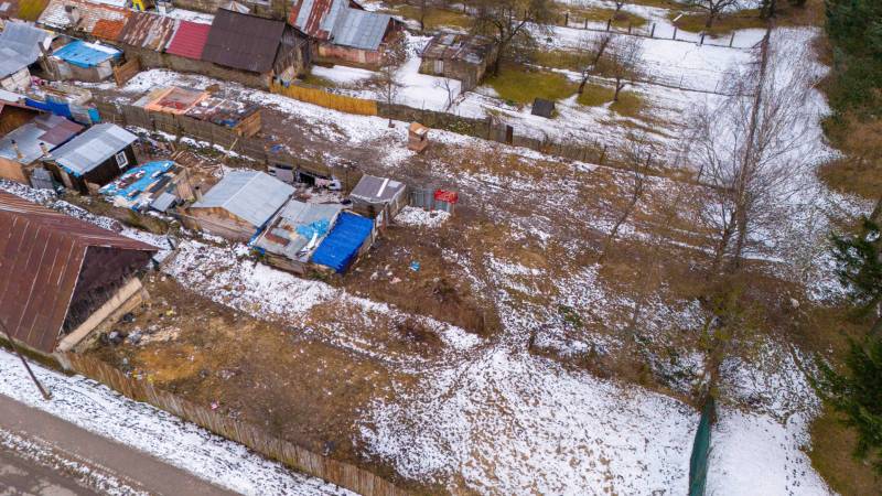 Téli kert Nálepkovóban havas házikókkal és fákkal, amelyek kontrasztot alkotnak a barna talajjal.
