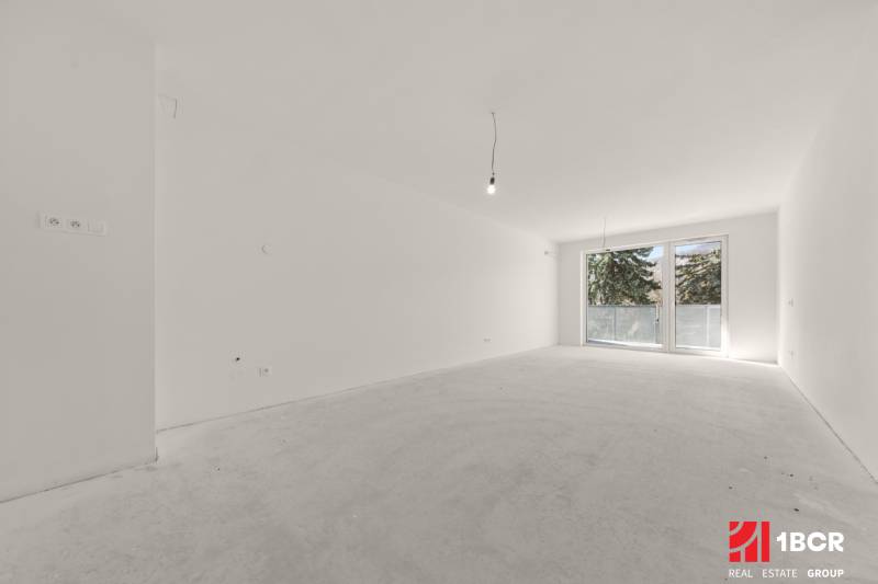 Tágas szoba egy 4 szobás lakásban nagy francia ablakkal és fehér falakkal.