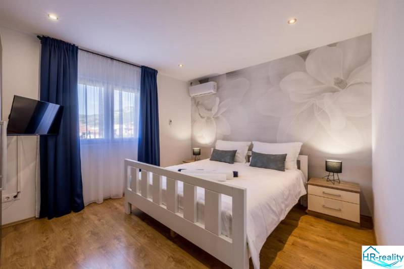 Világos hálószoba TV-vel, légkondicionálóval és fa dekorációjú padlóval a villában.