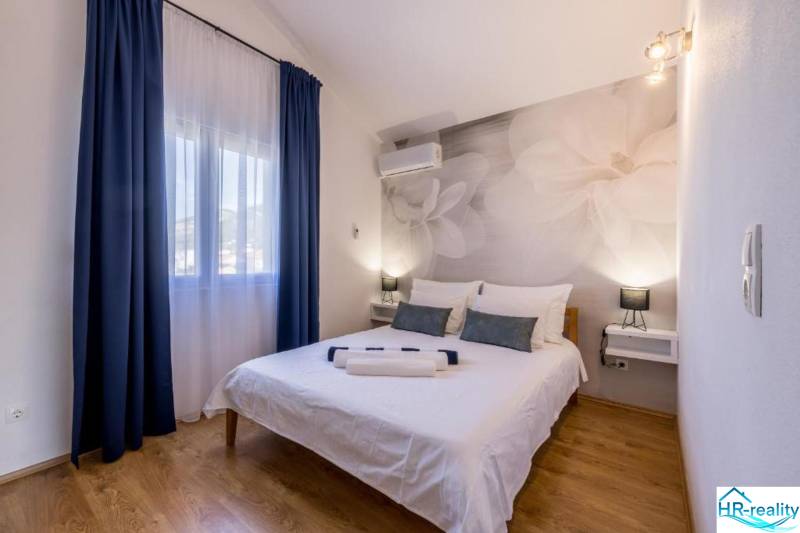 Hálószoba a villában nagy virágokkal a falon és fa dekorációjú padlóval.