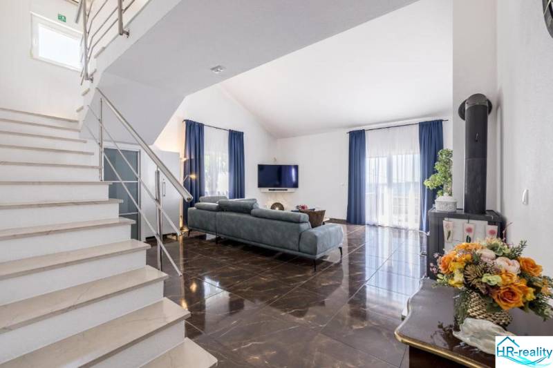 Nappali egy villában fényes padlóval és kék függönyökkel.